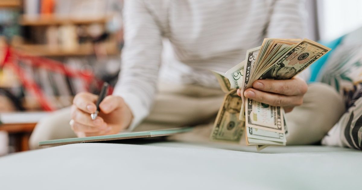 Person counting cash and writing a budget at home